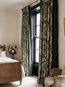 pair of Tropical Tales curtains framing a window in a luxury bedroom with a vintage wooden bed and velvet armchair.