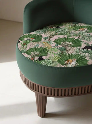 Close up of a rounded green armchair with a Tropical Tales fabric seat showcasing a leopard and dense jungle flora.