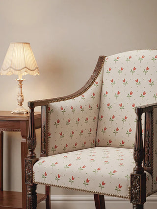 A high-back vintage wooden armchair upholstered in the Tulip Field fabric, paired with a classical table lamp.