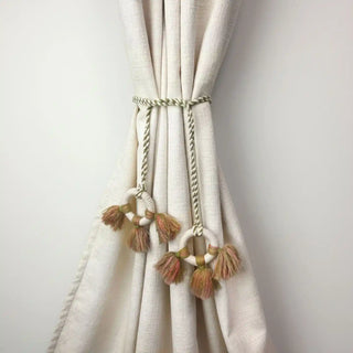 Springhaven Handcrafted Curtain Tieback secured on a cream curtain, showcasing the bohemian style of the macrame rings and tassels.
