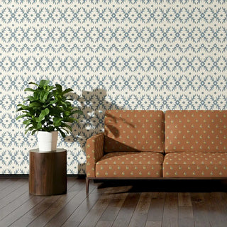 Sofa upholstered in Vasant Fabric with intricate floral accents against a patterned wall backdrop.