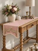The Veloura table runner in Dusty Rose & Ecru on a carved wooden console table with barley-twist legs, styled with flowers and brass accents.