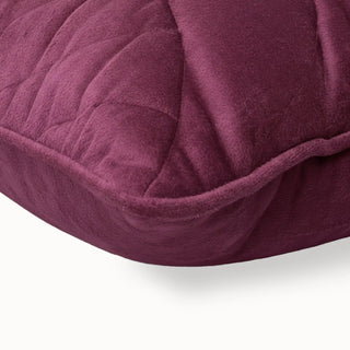 Close-up of the fawn velvet cushion corner showing the embroidery and patterned piping.