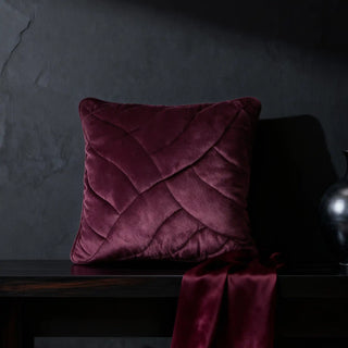 Single Velvet Dune Cushion displayed on a brown leather tufted sofa in a dark setting.