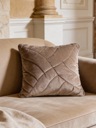 A luxury sandy-beige velvet cushion with a quilted lattice pattern styled on a matching velvet sofa in a classical room.
