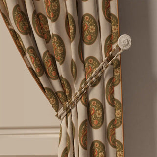 A close-up of the Vintage Blossom Pipin curtain tied back with a tasseled cord, highlighting its neat piped edge and the beautiful vintage pattern.