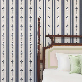 Bedroom wall styled with Vintage Navy & Beige Motif Stripe Wallpaper Roll, featuring alternating navy stripes and beige floral motifs paired with a traditional wooden bed and white bedding with pastel green cushions.