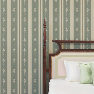 Bedroom wall styled with Vintage Olive & Beige Motif Stripe Wallpaper Roll, featuring muted olive stripes with beige floral motifs and a classic wooden bed with white and green cushions.