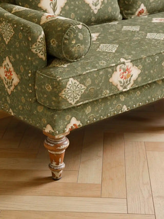 Close up of a plush sofa with brass nailhead trim upholstered in Viraasat Green floral fabric.