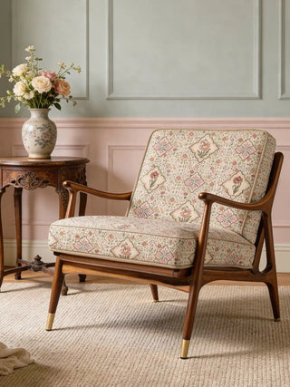 A contemporary rounded armchair upholstered in Viraasat Sepia floral fabric, styled against a striped wall.