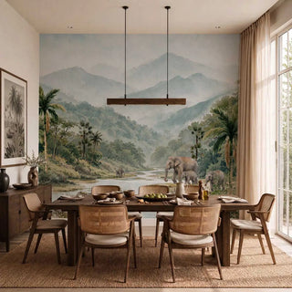 Wayanad Wilderness wall mural in sage and mist covering the full accent wall of a contemporary dining room with a walnut dining table, cane-back chairs, wooden pendant light, and linen curtains