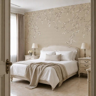 The Whispering Branches wallpaper mural in Sepia installed on a feature wall in a bedroom, trailing white blossom branches above an upholstered bed frame. view-bedroom
