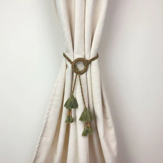 Woodland Essence Handcrafted Curtain Holdback cinched on a cream curtain, showcasing the earthy green tassels and unique ring design.