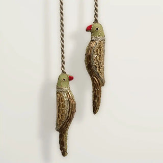 Close-up detail of green and gold beaded parrot curtain holdbacks showing intricate zardozi handwork.