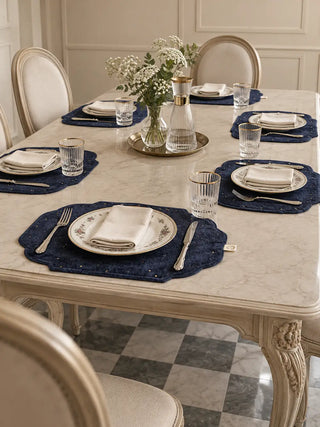 Zarfshan navy velvet placemats set for six on a marble-topped table with a glass carafe and florals.