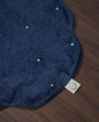 Close-up of a Zarfshan navy velvet placemat showing scattered sequins and its woven brand label.