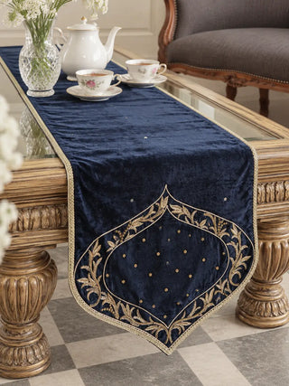 The Zarfshan Velvet Table Runner in Navy & Gold on a carved coffee table, styled with a floral tea service.