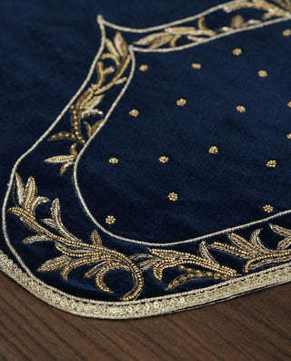 Close-up of a Zarfshan navy velvet placemat showing scattered sequins and its woven brand label.