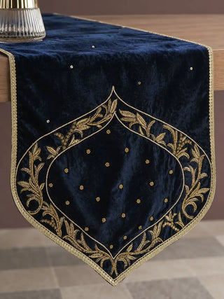 The Zarfshan Velvet Table Runner in Navy & Gold draped over a table edge, showing its pointed arch end with gold embroidery.