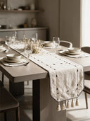 The Zarin Trace table runner in Natural & Black styled along a wooden dining table set with ceramic dinnerware, wine glasses and a dried floral centrepiece.