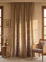 The Zarqash hand-embroidered luxury gold-beige velvet curtains styled inside an elegant traditional sitting room next to a carved wooden chair.