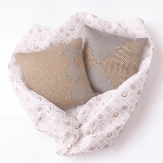 Zayan and Sirrocco woven pillows styled on pink quilted bedding with celestial and garden motifs, showing complementary layered texture and color coordination.