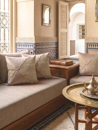 Pair of Zayan Weave cushion covers styled on a daybed beside a carved wooden table with Moroccan blue tile detailing