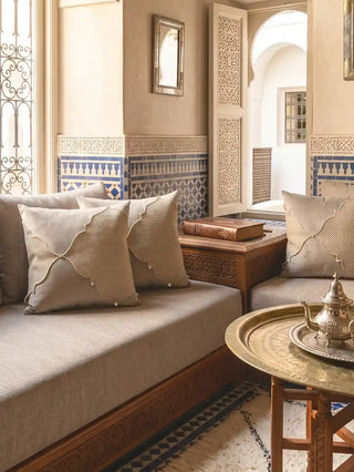 A series of Zayan Weave cushion covers styled elegantly across a low-profile banquette sofa inside a traditional Moroccan riad lounge.