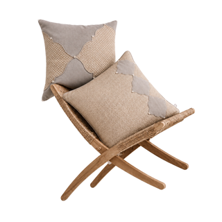 The Zayan Weave & Sirocco cushion set styled on a woven rattan bench, showing a scalloped colour-block cushion pairing grey suede-like fabric with a woven jute-textured panel, and a second cushion with a scalloped border panel over the same woven ground, both finished with bead trim accents.